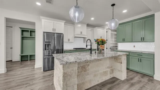 a large kitchen with stainless steel appliances kitchen island granite countertop a refrigerator and a sink