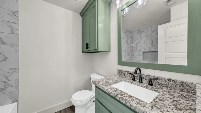 a bathroom with a granite countertop sink a toilet and a mirror