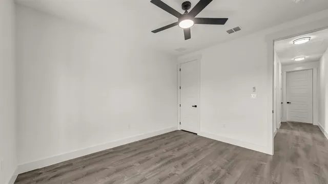 an empty room with wooden floor and ceiling fan