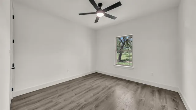 an empty room with a window and a ceiling fan