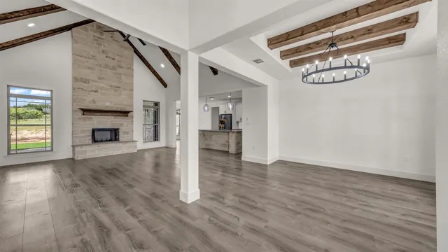 a view of an empty room with wooden floor fireplace and a window