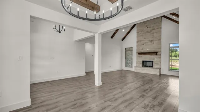 a view of an empty room with wooden floor and a fireplace
