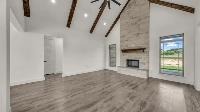 an empty room with wooden floor fireplace and windows