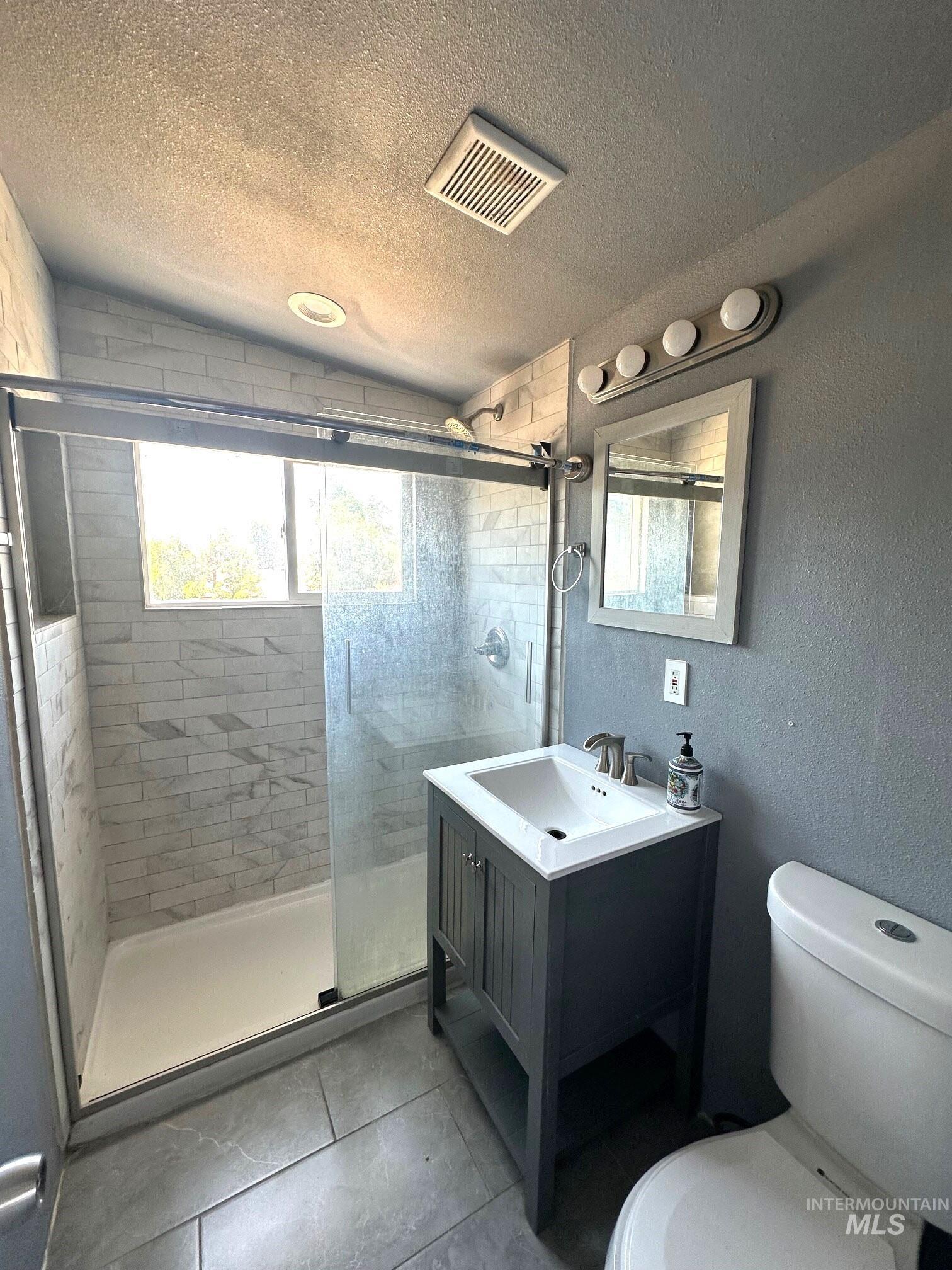 787 Southwest 3rd Street Ontario, OR 97914 - Photo 15 of 22 Full bath with healthy amount of natural light, a textured ceiling, a stall shower, a textured wall, and vanity