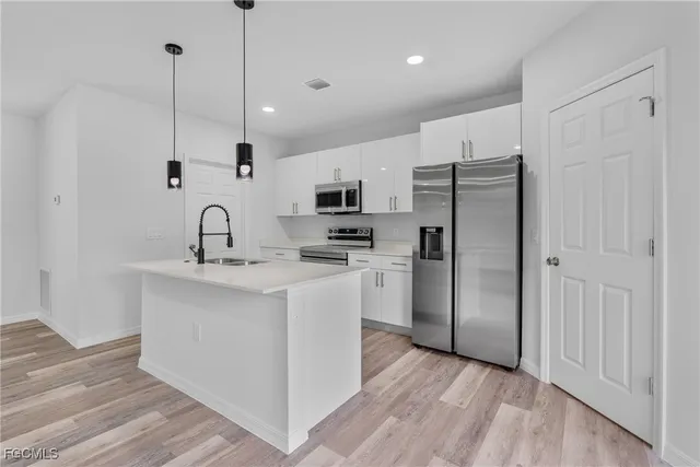 a kitchen with stainless steel appliances kitchen island a white cabinets and a wooden floor