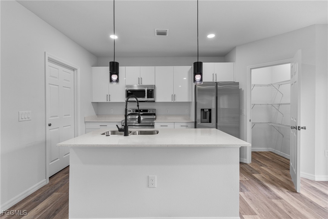 945 Butler Street East Lehigh Acres, FL 33974 - Photo 12 of 34 a kitchen with kitchen island a sink stainless steel appliances and cabinets