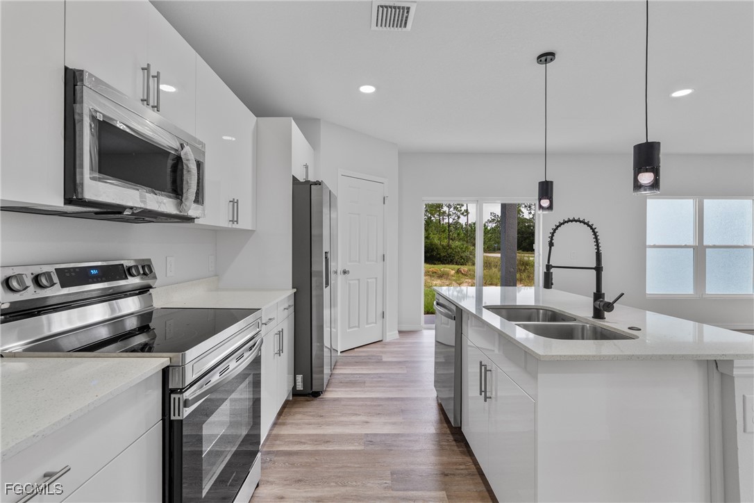 945 Butler Street East Lehigh Acres, FL 33974 - Photo 14 of 34 a kitchen with stainless steel appliances granite countertop a sink a stove and a refrigerator