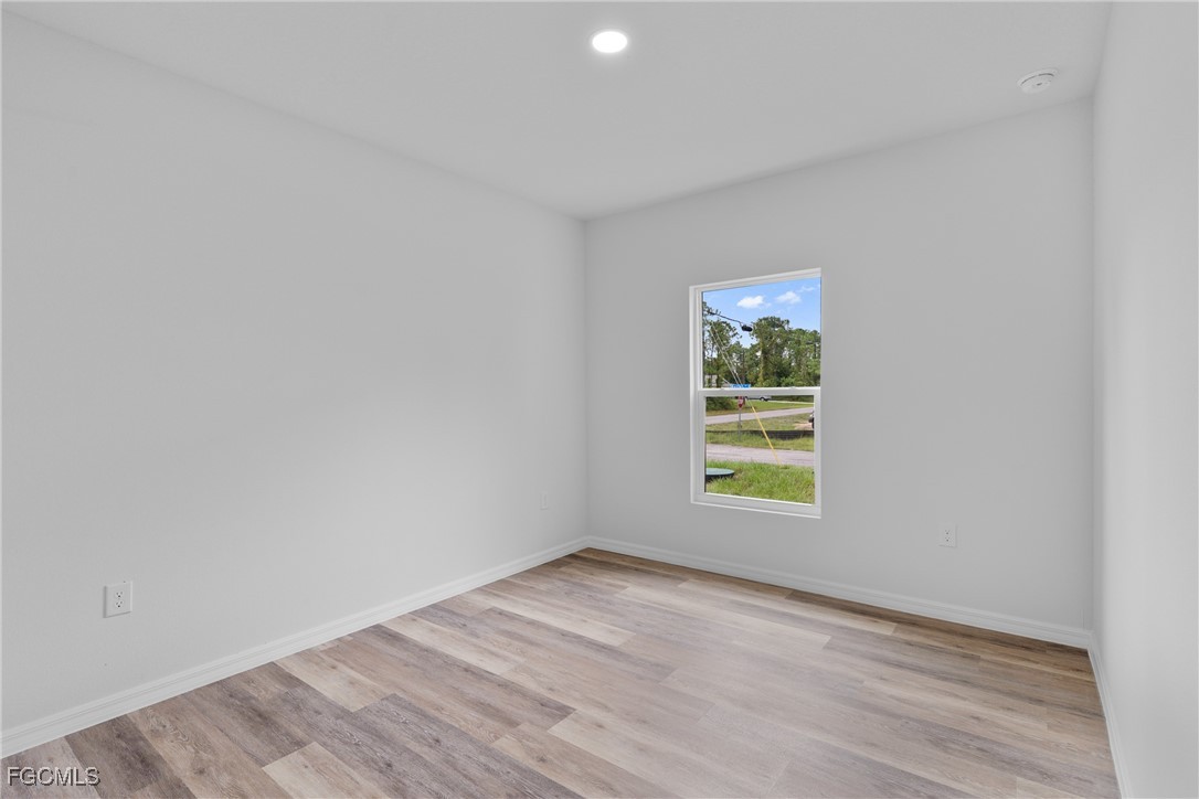 945 Butler Street East Lehigh Acres, FL 33974 - Photo 19 of 34 wooden floor in an empty room with a window