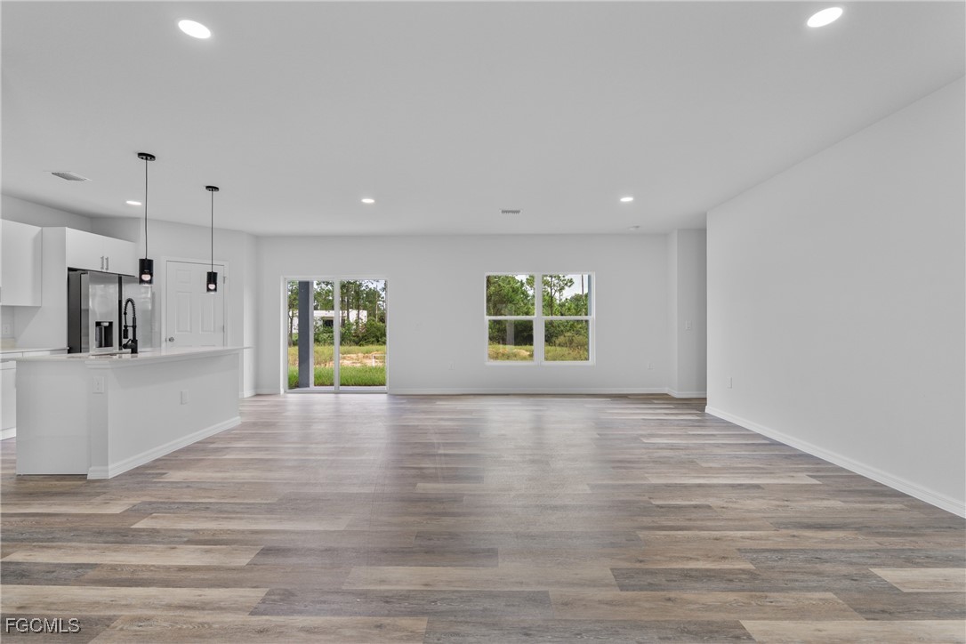 945 Butler Street East Lehigh Acres, FL 33974 - Photo 7 of 34 a view of an empty room with window and wooden floor