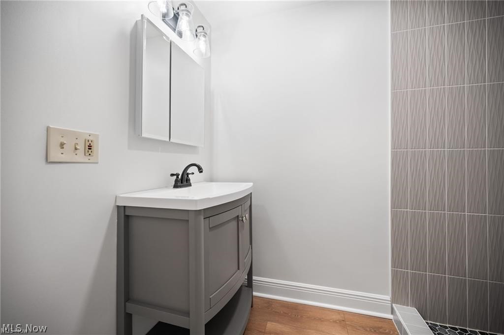 28300 Aurora Road Solon, OH 44139 - Photo 32 of 36 Bathroom vanity featuring a curved white countertop, dark gray cabinetry with brushed nickel hardware, and a matte black single-handle faucet