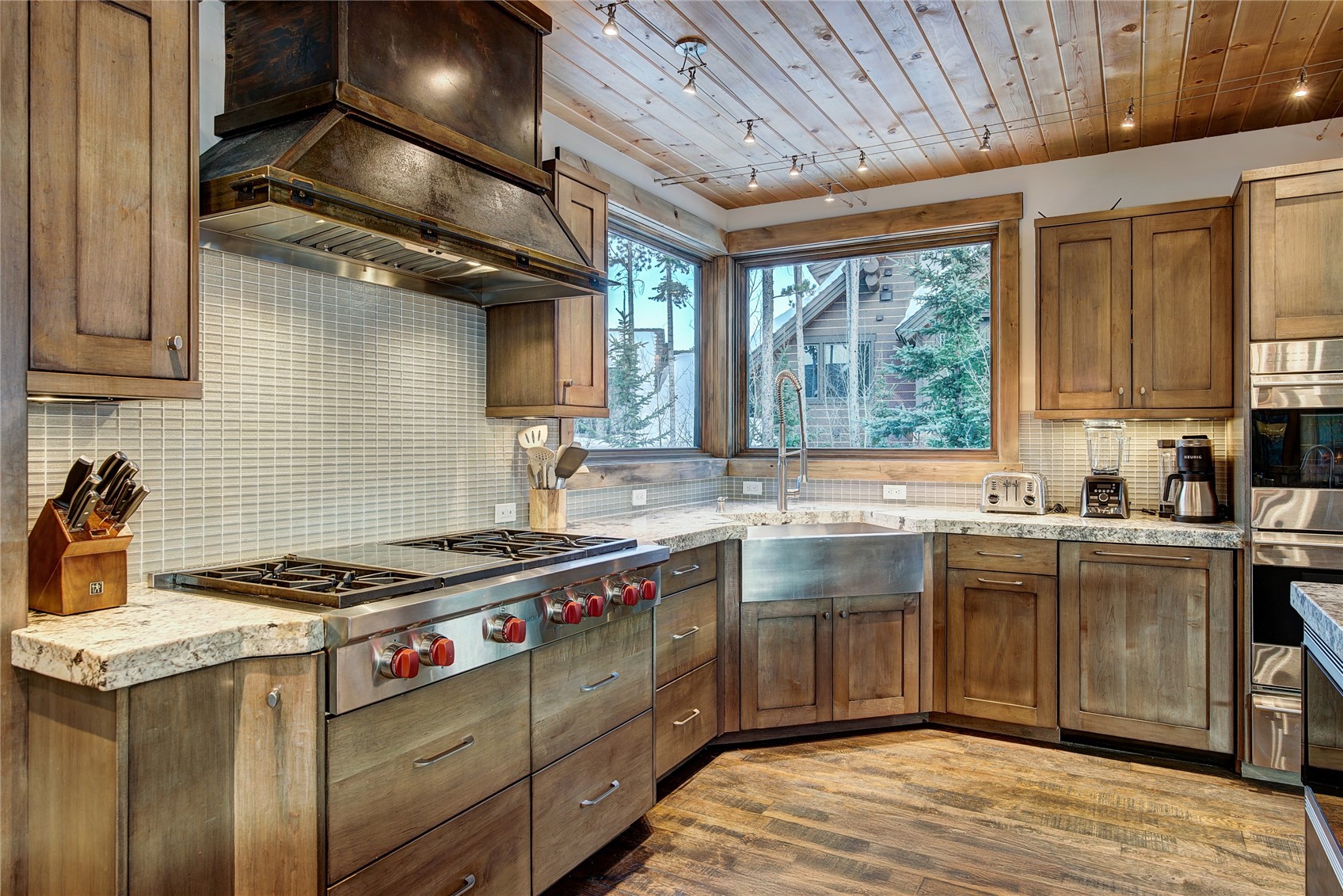 422 Timbertrail Road Breckenridge, CO 80424 - Photo 21 of 50 Kitchen with wood ceiling, brown cabinets, premium range hood, backsplash, and stainless steel appliances
