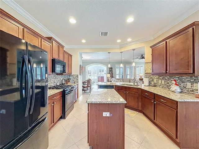 a kitchen with stainless steel appliances kitchen island granite countertop a refrigerator a stove a sink a dining table and chairs