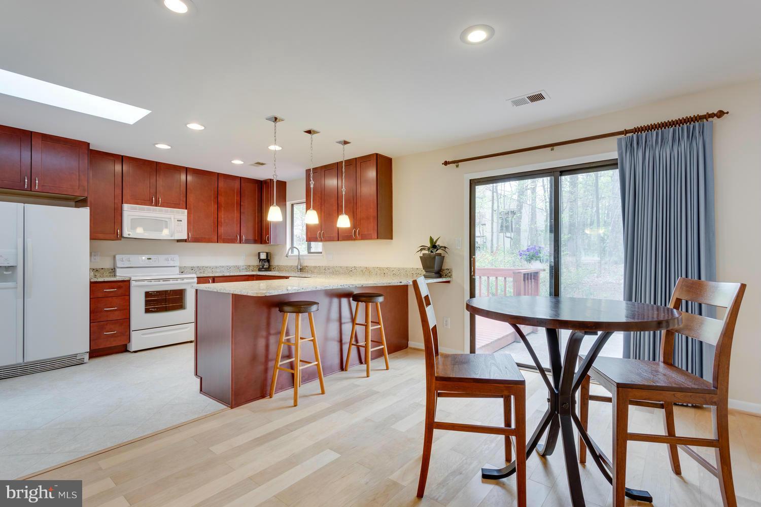 12348 Lima Lane Reston, VA 20191 - Photo 10 of 26 a open kitchen with stainless steel appliances granite countertop a stove top oven a sink a dining table and chairs with wooden floor