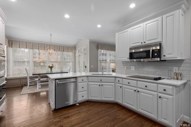 a kitchen with stainless steel appliances a stove a sink cabinets and wooden floor