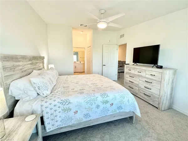 a spacious bedroom with a bed and a flat screen tv