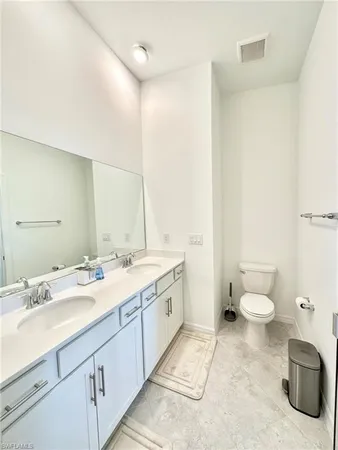 a bathroom with a double vanity sink toilet and a mirror