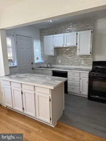 a kitchen with kitchen island granite countertop a sink cabinets and wooden floor
