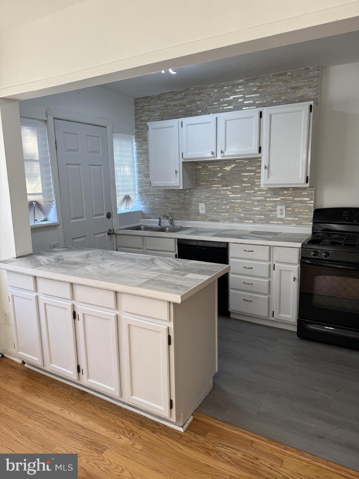 1343 Queen Street Northeast Washington, DC 20002 - Photo 4 of 6 a kitchen with kitchen island granite countertop a sink cabinets and wooden floor