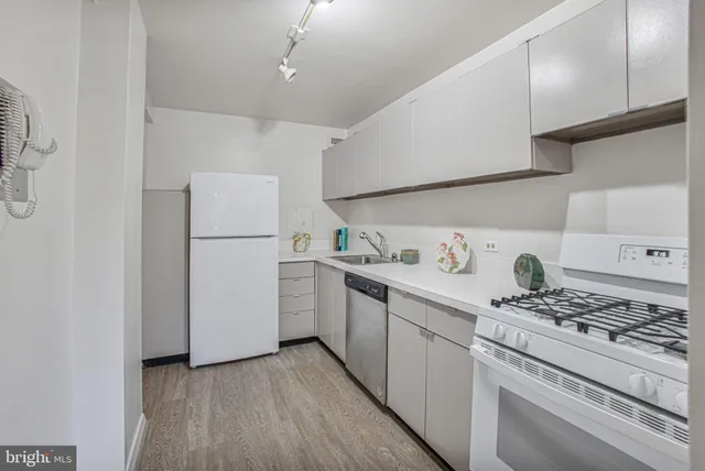a kitchen with a refrigerator a stove and wooden floor