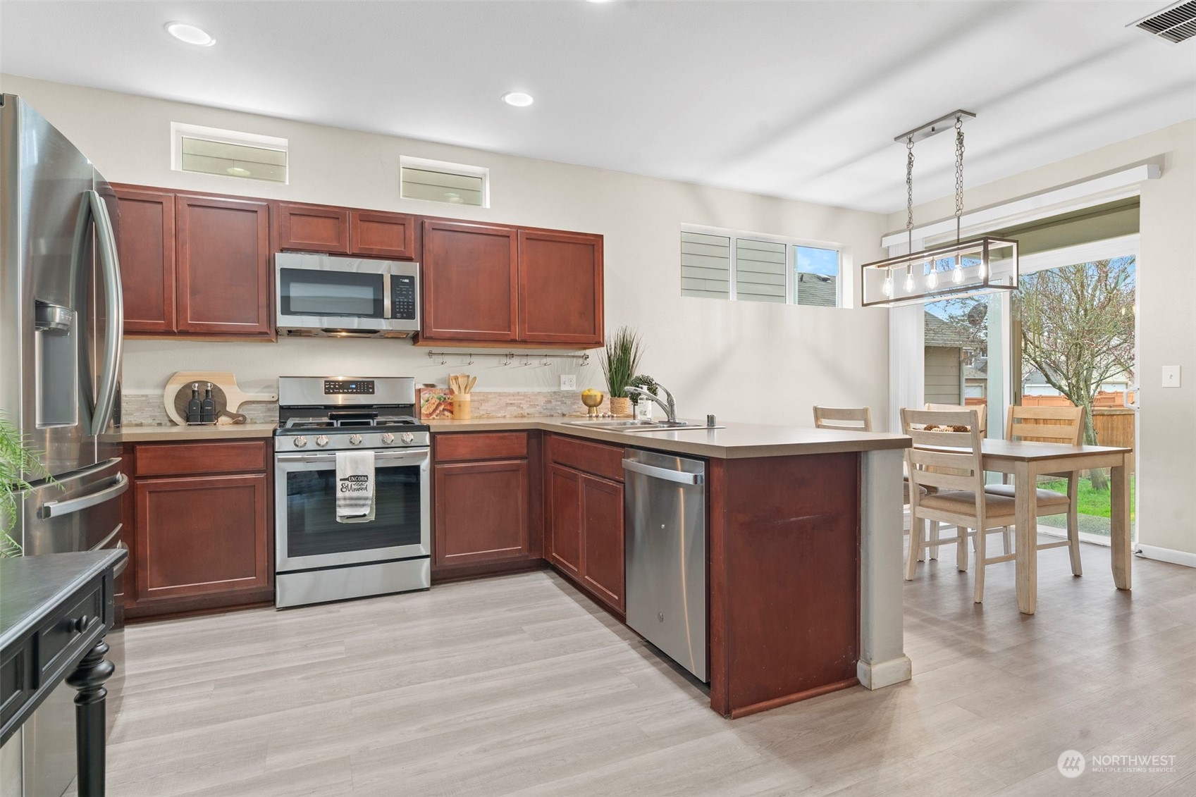 9175 Periwinkle Loop Northeast Lacey, WA 98516 - Photo 7 of 29 a kitchen with stainless steel appliances granite countertop a stove top oven a sink dishwasher a refrigerator and a dining table with wooden floor