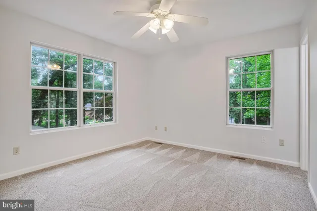 an empty room with a window and a fan