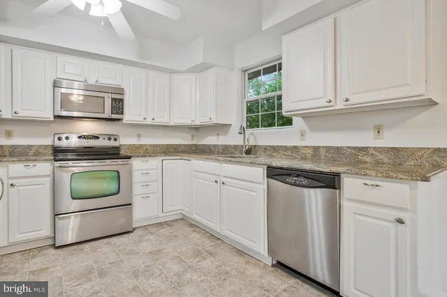 a kitchen with granite countertop white cabinets and white stainless steel appliances