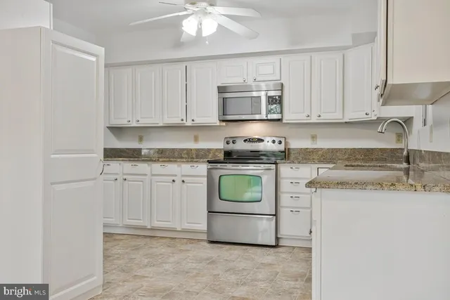 a kitchen with stainless steel appliances granite countertop a sink a stove a microwave and cabinets
