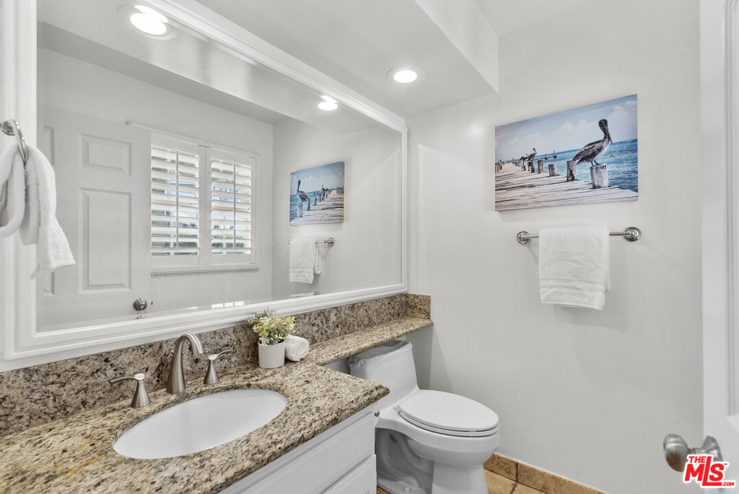 18779 Willowtree Lane Porter Ranch, CA 91326 - Photo 27 of 63 a bathroom with a granite countertop toilet a sink and a mirror