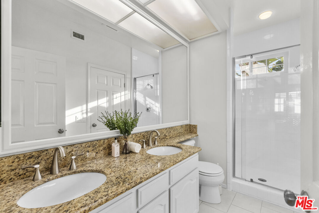 18779 Willowtree Lane Porter Ranch, CA 91326 - Photo 48 of 63 a bathroom with a granite countertop sink a toilet and a mirror