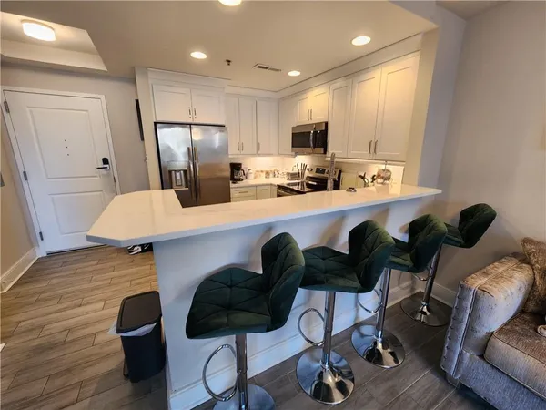 a kitchen with stainless steel appliances granite countertop a refrigerator a stove a sink dishwasher and white cabinets with wooden floor