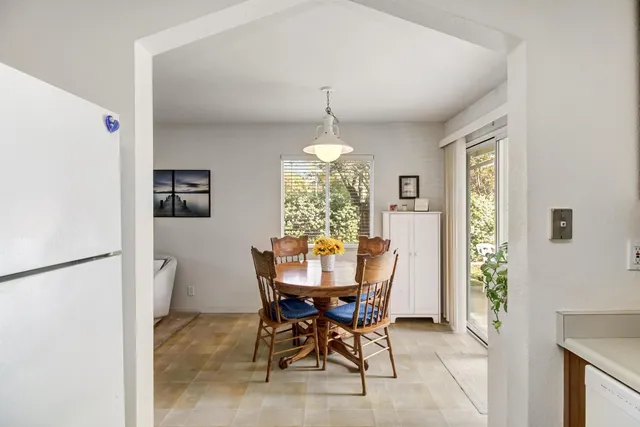a view of a backyard with table and chairs potted plants and large tree