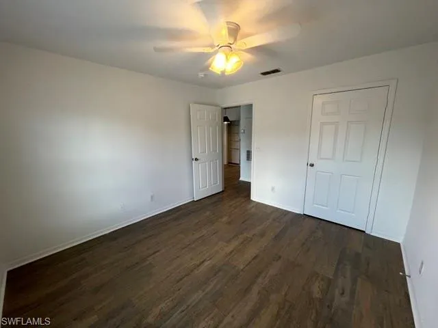 an empty room with wooden floor and a ceiling fan