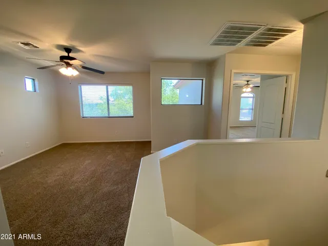 a view of a big room with windows and ceiling fan