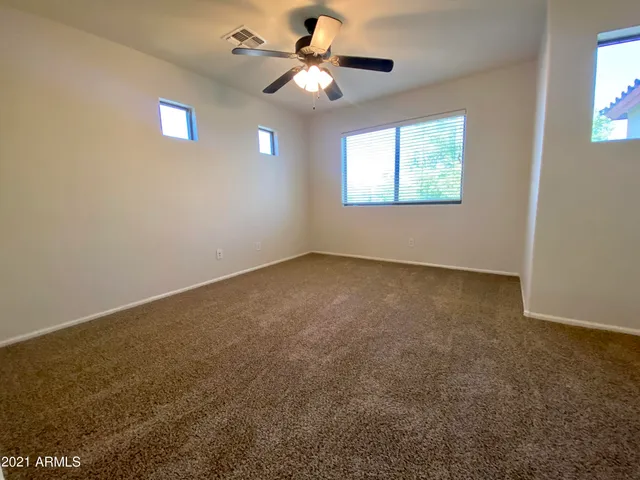 an empty room with windows and fan