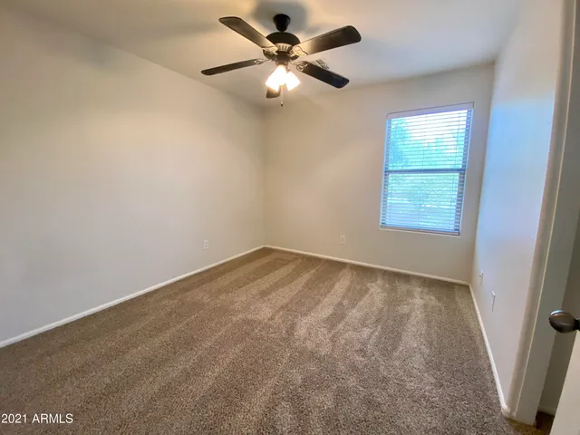 an empty room with a window and a fan