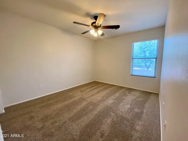 an empty room with a window and a ceiling fan