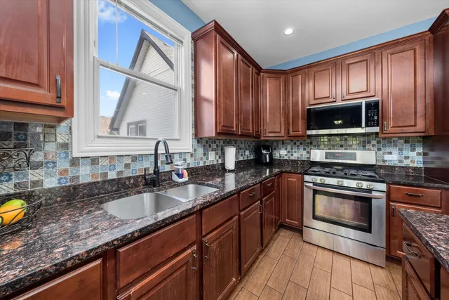 a kitchen with granite countertop a stove a sink and a microwave