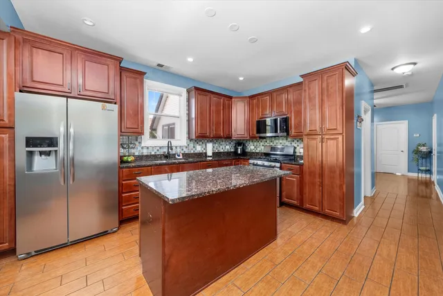 a kitchen with stainless steel appliances granite countertop a refrigerator a sink dishwasher a stove with wooden cabinets and a refrigerator