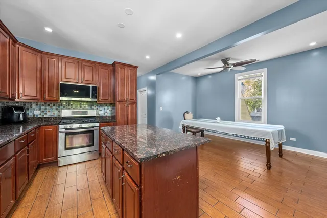 a kitchen with granite countertop a stove top oven a sink dishwasher a dining table and chairs with wooden floor