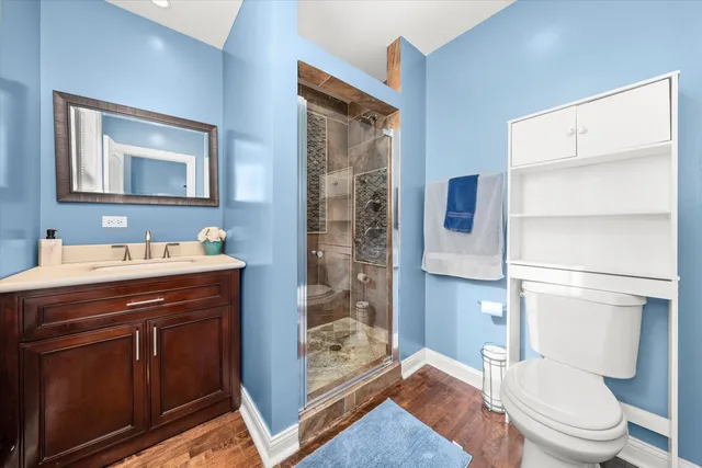 a spacious bathroom with a granite countertop sink a toilet a mirror and shower