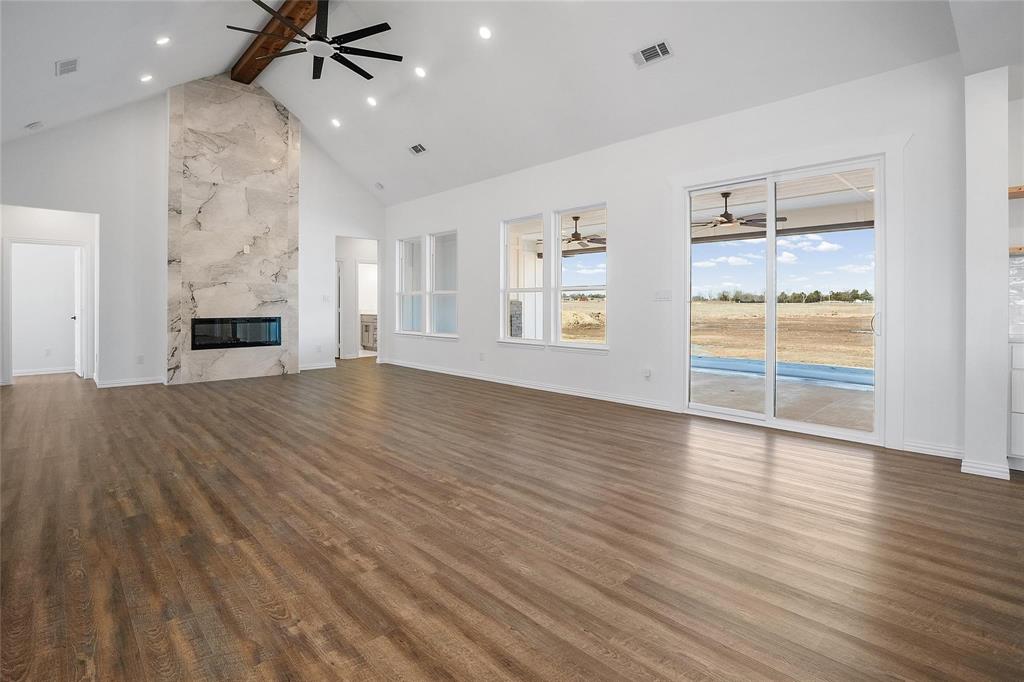 3093 Willow Road Celeste, TX 75423 - Photo 13 of 40 an empty room with wooden floor fireplace and windows