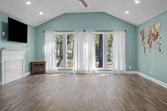 an empty room with wooden floor and windows