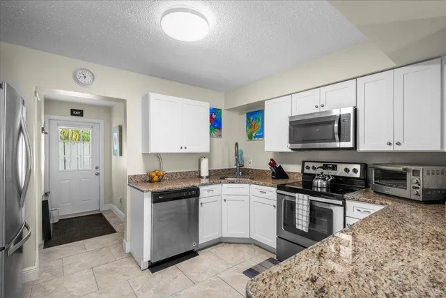 a kitchen with stainless steel appliances granite countertop a stove top oven a sink a counter space and cabinets