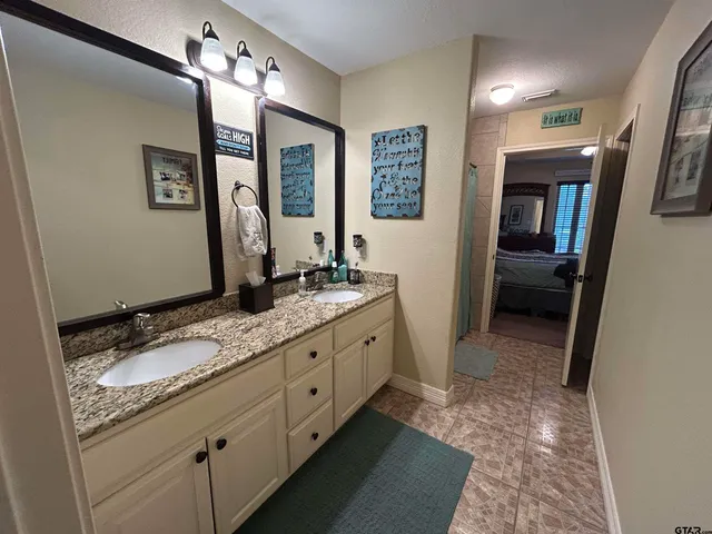 a bathroom with a granite countertop double vanity sink and a mirror