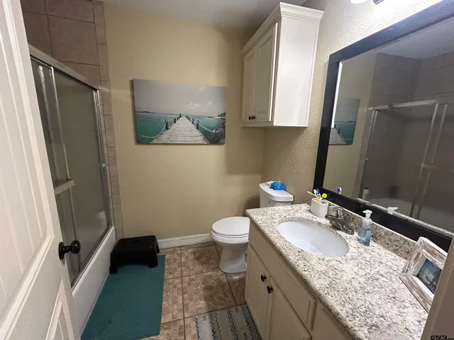 a bathroom with a granite countertop sink toilet and shower