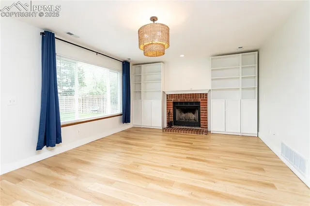 a view of an empty room with a window and fireplace