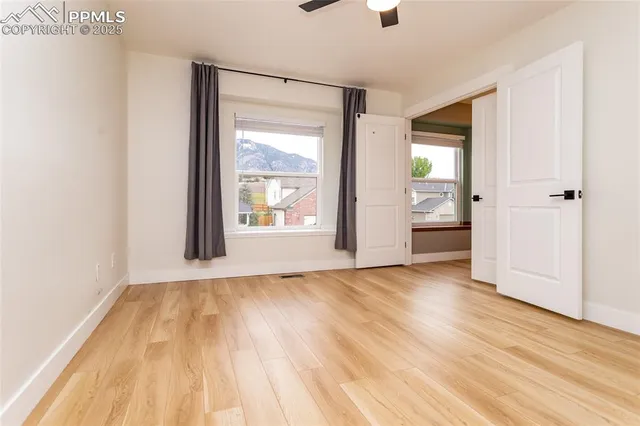 a view of an empty room with wooden floor and a window