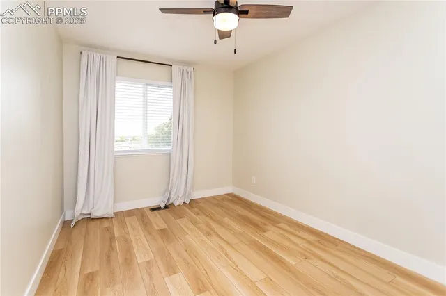 an empty room with a window and a ceiling fan