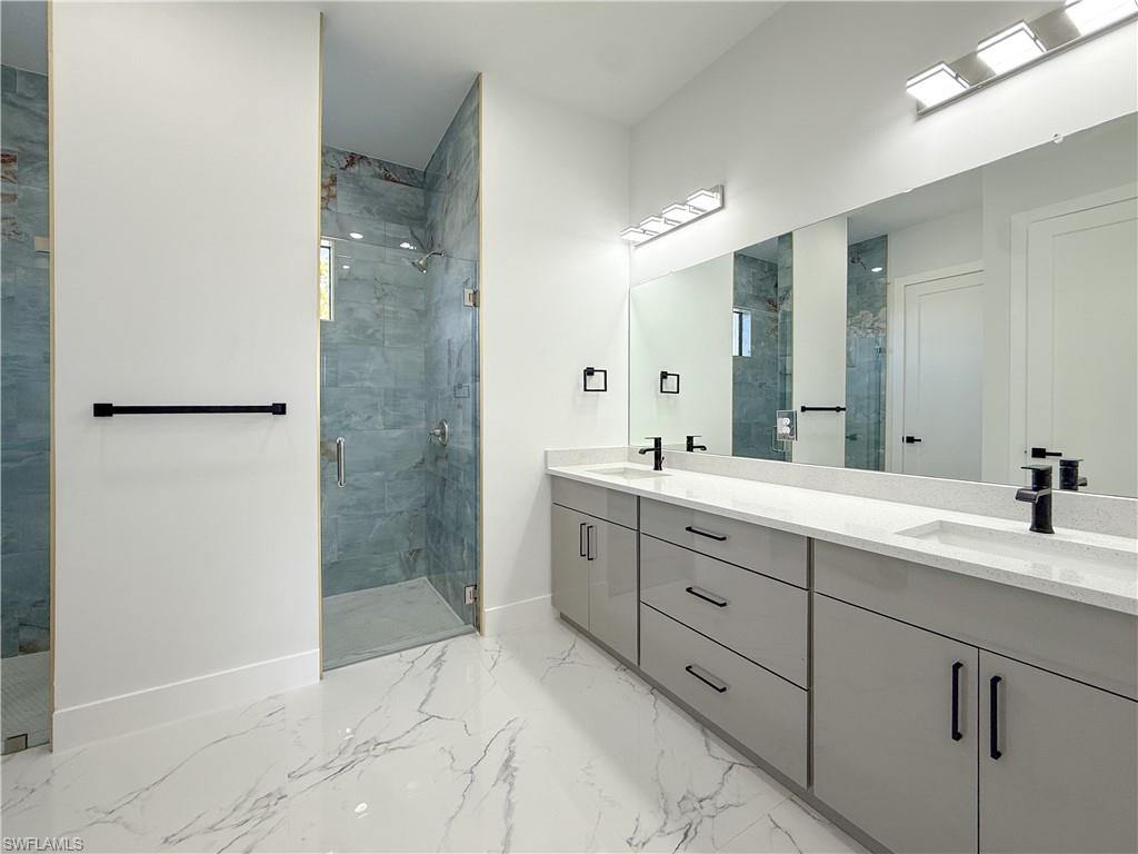436 Rathburn Street Lehigh Acres, FL 33974 - Photo 10 of 22 Full bathroom with a stall shower, double vanity, and light marble finish floors