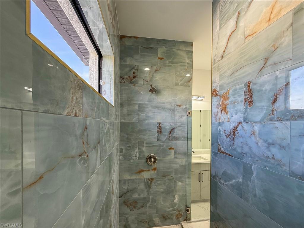 436 Rathburn Street Lehigh Acres, FL 33974 - Photo 12 of 22 Full bath with a marble finish shower, vanity, and tile walls